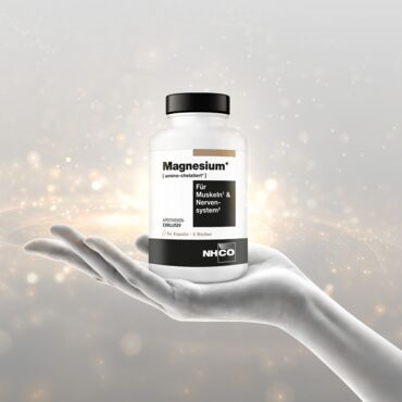 Hand präsentiert NHCO Magnesium-Nahrungsergänzungsmittel vor funkelndem Hintergrund.