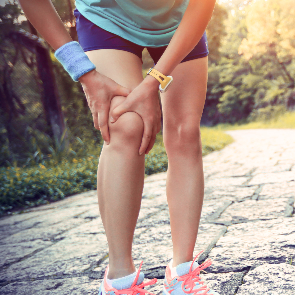 Läuferin hält sich das Knie, möglicher Hinweis auf Nährstoffmangel und Bedarf an Aminosäurekomplexen.