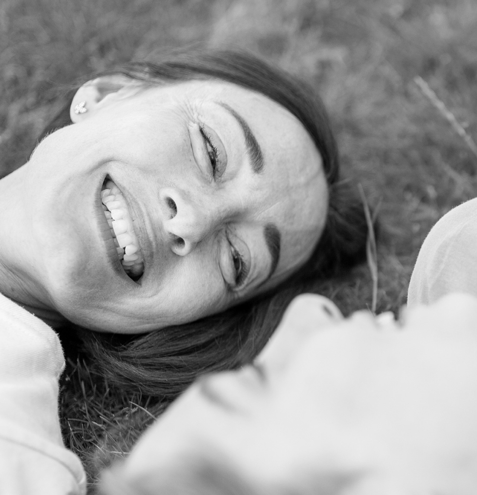 Lächelnde Person liegt im Gras, symbolisiert Wohlbefinden durch optimale Nährstoffversorgung.